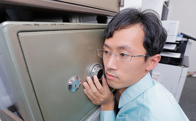金庫のダイヤルを回して番号を探って鍵を開ける